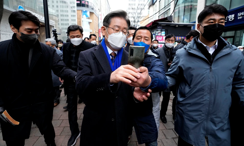 Lee Jae-myung, center, the presidential election candidate of the ruling Democratic Party, takes pictures with his supporter after a press conference in Seoul, South Korea, Monday, Feb. 14, 2022. (AP)