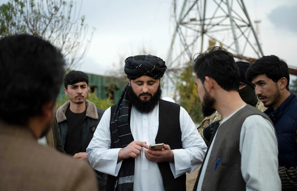 This photo taken on January 17, 2022 shows Maymana mayor Damullah Mohibullah Mowaffaq (C) looking at his mobile phone in Maymana, capital of Afghanistan's northwestern Faryab province. (AFP)