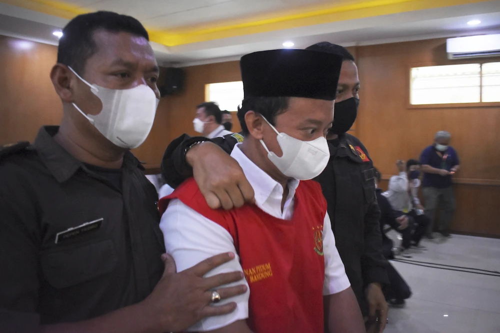 Herry Wirawan, center, the principal of a girls Islamic boarding school accused of raping his students, with security officers during a sentencing hearing at a district court in Bandung, West Java. (AP)