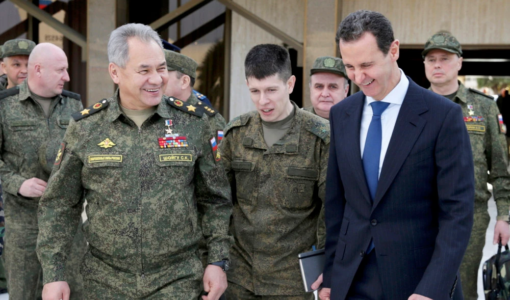In this photo taken on Tuesday, Feb. 15, 2022, Russian Defense Minister Sergei Shoigu, left, and Syrian President Bashar Assad, right, smile during their meeting in Damascus, Syria. (AP)