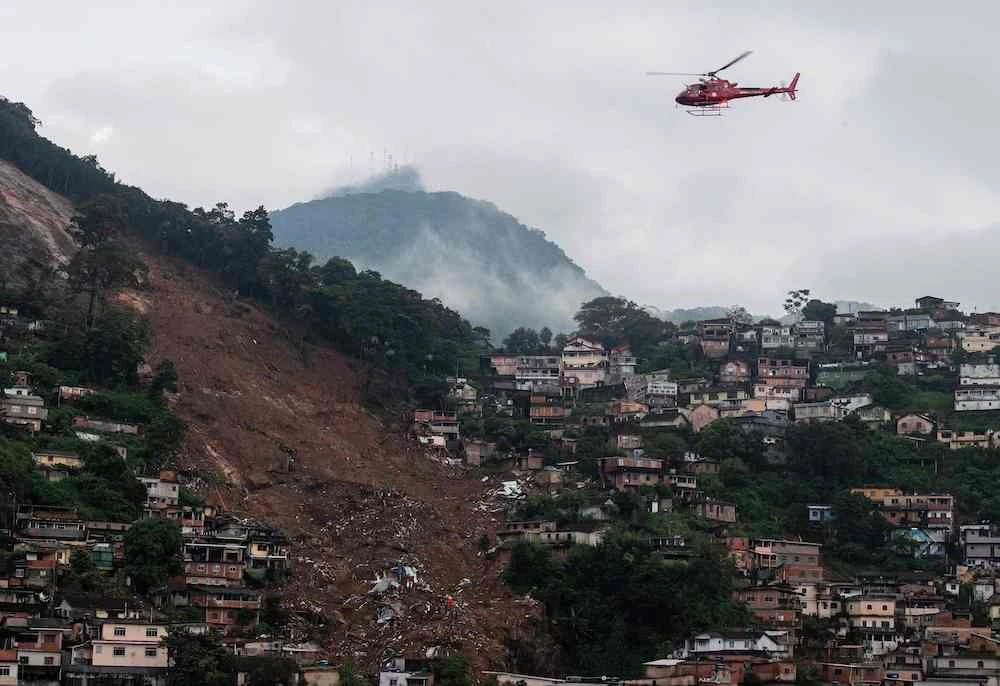 An emergency service helicopter flies over a large landslide caused by severe flash floods in Petropolis, Brazil, on Feb. 18, 2022. (AFP)