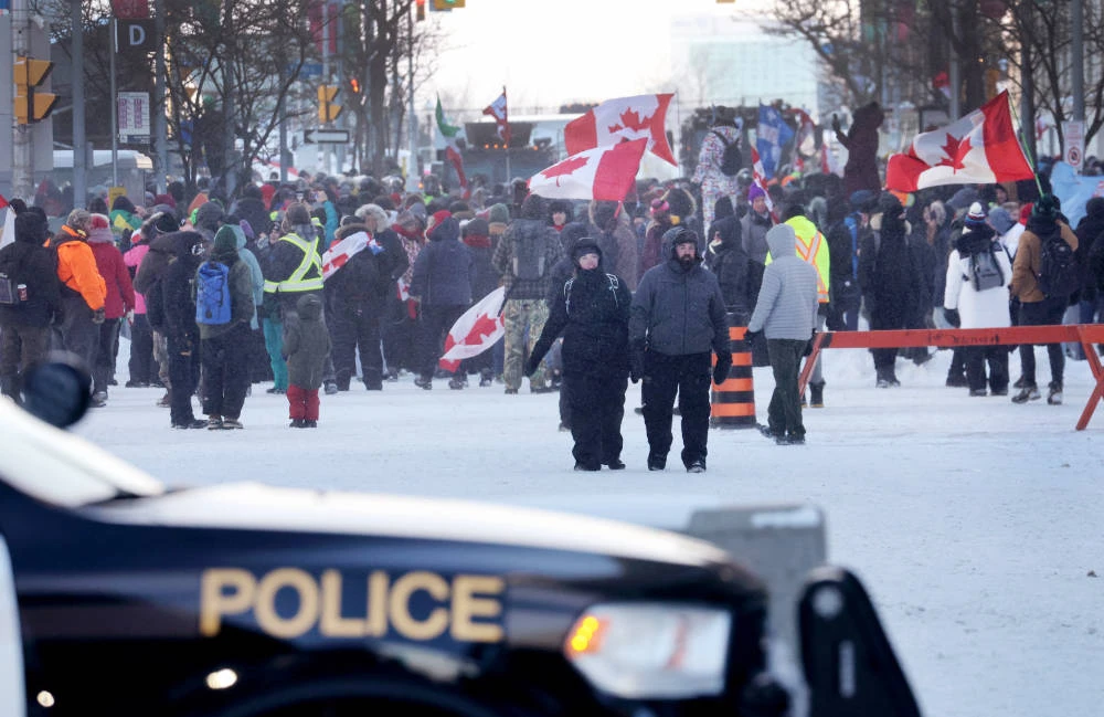 Police keep watch as demonstrators participating in a protest organized by truck drivers opposing vaccine mandates continue to gather on the streets in the day on February 19, 2022 in Ottawa. (AFP)