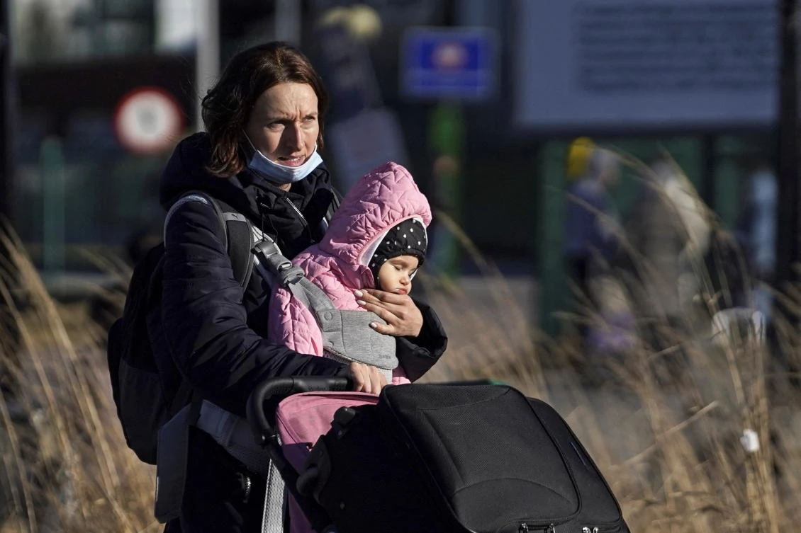 A mother carries her young daughter across the border, to escape the violence in Ukraine, at Medyka, Poland, Feb. 24, 2022. (Reuters)