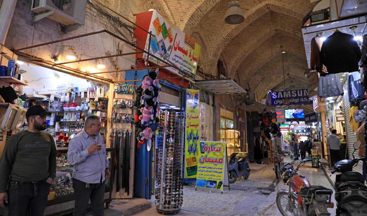Iraqis walk at a market in the city of Amara, the capital of Iraq's southeastern Maysan province, on February 16, 2022. (AFP)