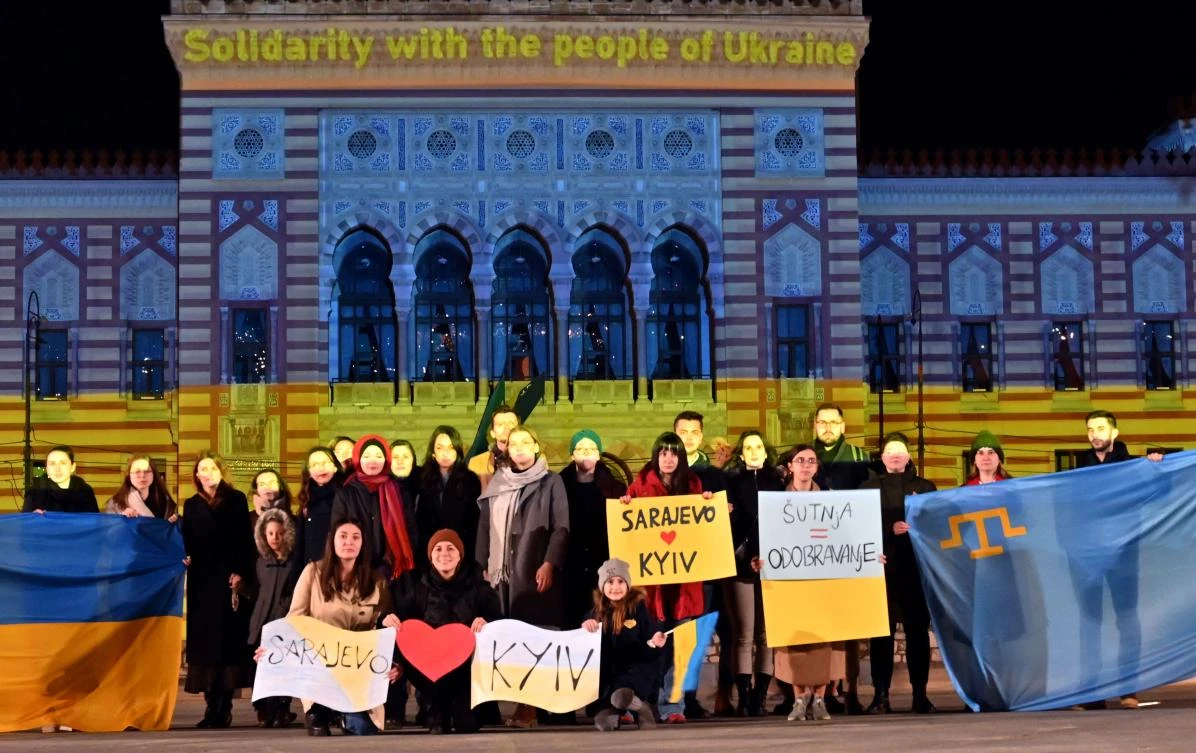 A small group of citizens gather in front of the Sarajevo city hall lit up with the colors of the Ukrainian flag, late on Thursday. (AFP)