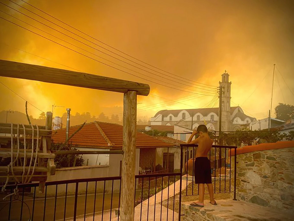 A young boy watches as wildfires close in on his village in Cyprus. (Reuters)