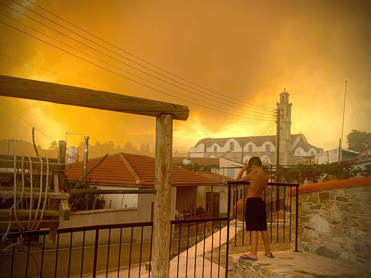 A young boy watches as wildfires close in on his village in Cyprus. (Reuters)