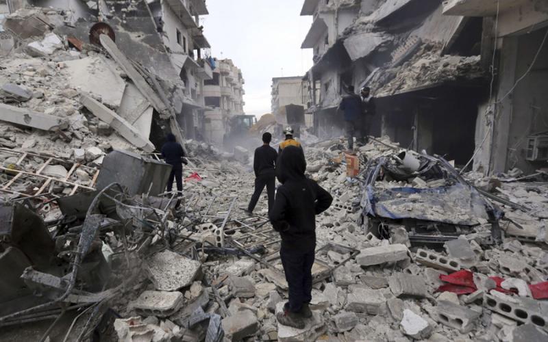 Syrians stand on the rubble of a destroyed building, strewn across a street, after Assad regime airstrikes, Ariha, Idlib province, Syria, Jan. 30, 2020. (AP Photo)