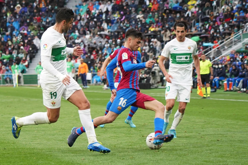 Barcelona's Pedri, centre, controls the ball during a Spanish La Liga soccer match between Elche and Barcelona at the Martinez Valero stadium in Elche, Spain, Sunday, March 6, 2022. (AP)