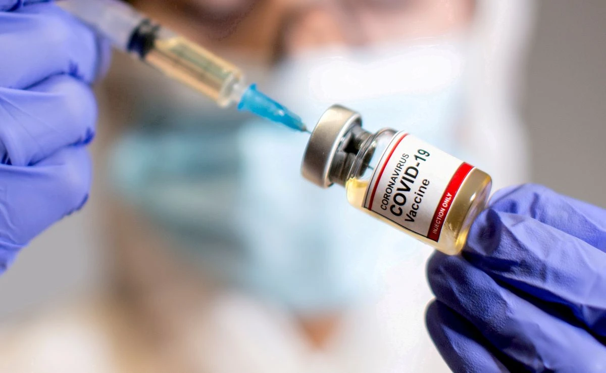 A woman holds a small bottle labelled with a "Coronavirus COVID-19 Vaccine" sticker and a medical syringe in this illustration taken October 30, 2020. (Reuters)