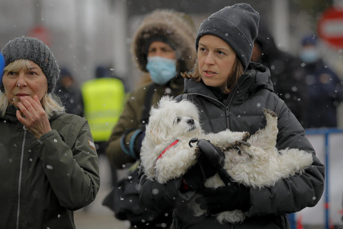 A refugee fleeing the conflict from neighboring Ukraine holds a small dog in her arms, at the Romanian-Ukrainian border, in Siret, Romania on Monday. (AP)