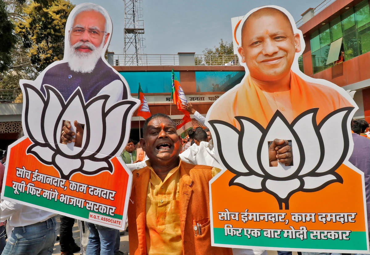 A BJP supporter is pictured with cut-outs of PM Narendra Modi and Chief Minister of Uttar Pradesh Yogi Adityanath after learning of the initial poll results Thursday. (Reuters)