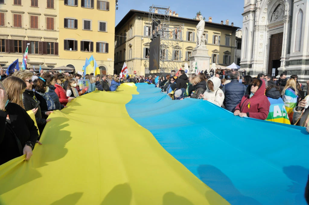 People gather to watch Ukrainian President Volodymyr Zelensky speak via a live video link on a screen during an anti-war demonstration 'Cities stand with Ukraine' in Piazza Santa Croce on March 12, 2022 in Florence, Italy. (Getty)