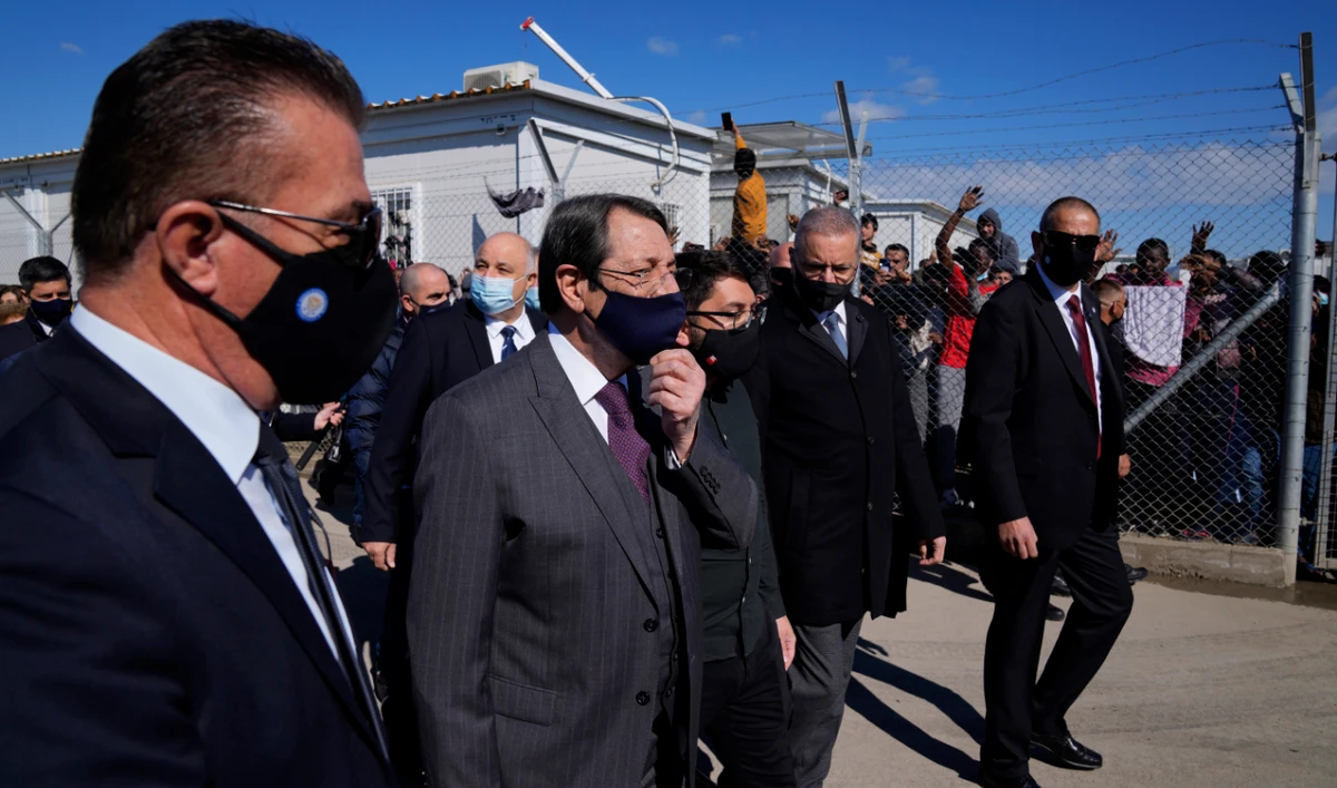 Cyprus' president, second left, adjusts his face mask as he walk inside the Pournara migrant reception center in Kokkinotrimithia outside of capital Nicosia, Cyprus, on Monday, March 14, 2022. (AP)