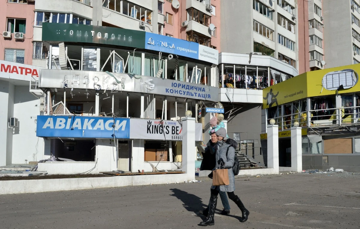 A family walks past a shopping centre damaged by recent shelling in Kharkiv on Tuesday, amid the ongoing Russia's invasion of Ukraine. AFP