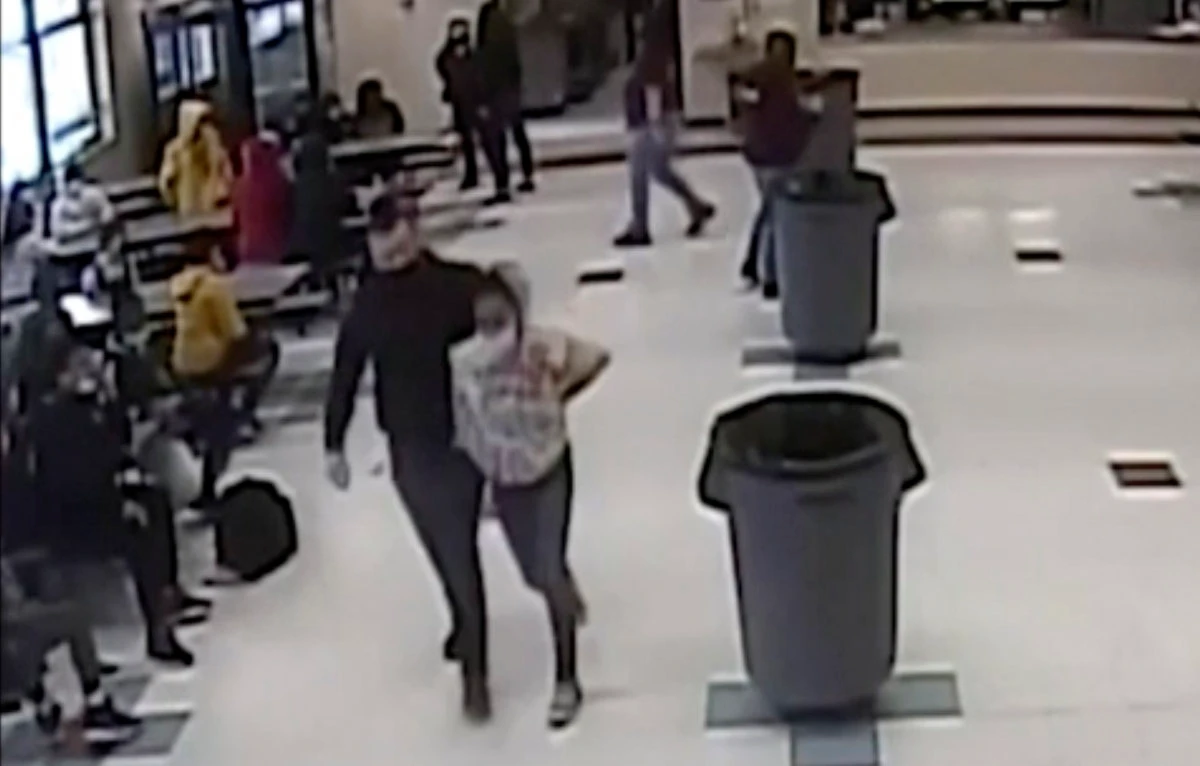 In this frame grab from surveillance video, an off-duty police officer escorts a 12-year-old student out of a school cafeteria following a lunchtime fight in Kenosha, Wisconsin, on March 4, 2022. (Kenosha Unified School video District via AP)