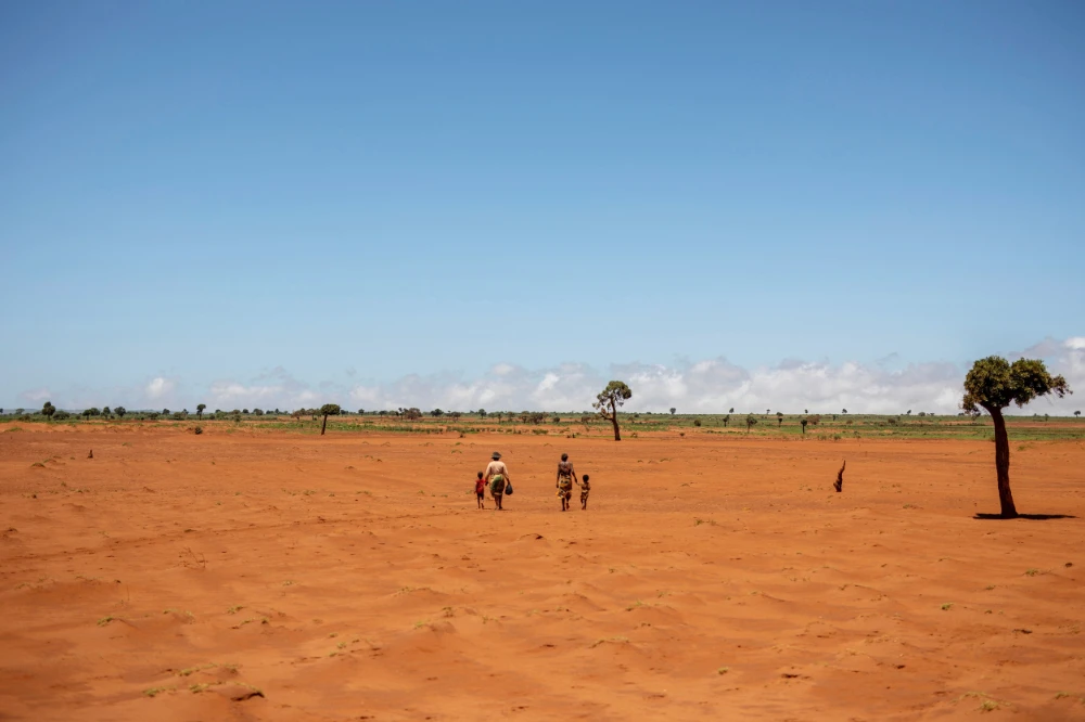 Tarira and her son Avoraza, 4, walk through a field covered with red sand in Anjeky Beanatara, Androy region, Madagascar, February 11, 2022. (REUTERS)