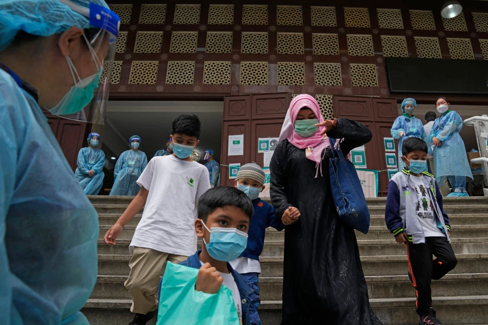 A family leave after receiving doses of the Pfizer-BioNTech COVID-19 coronavirus vaccine at a community vaccination center at the Kowloon Mosque And Islamic Centre in Hong Kong, Saturday, March 19, 2022. (AP)
