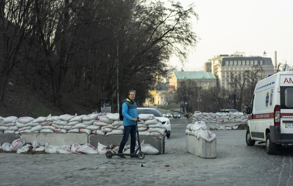A man riding an electric scooter near barricades in Kyiv, where Russian journalist Oksana Baulina for the investigative news outlet The Insider was killed in a residential neighborhood on Wednesday. (AP)