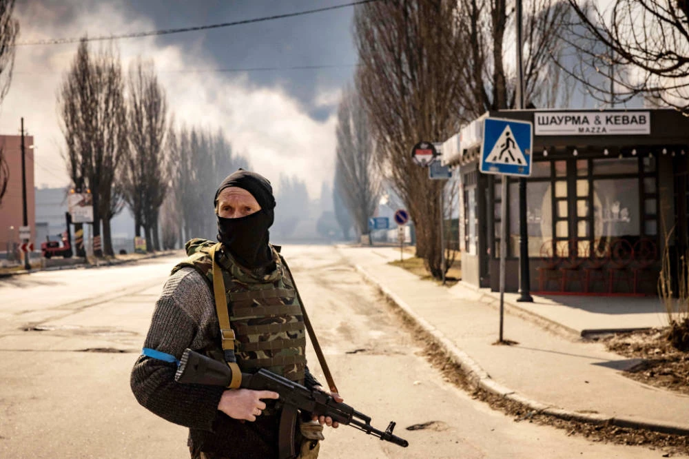 A Ukrainian serviceman stands guard near a burning warehouse hit by a Russian shell in the suburbs of Kyiv on March 24, 2022. (AFP)