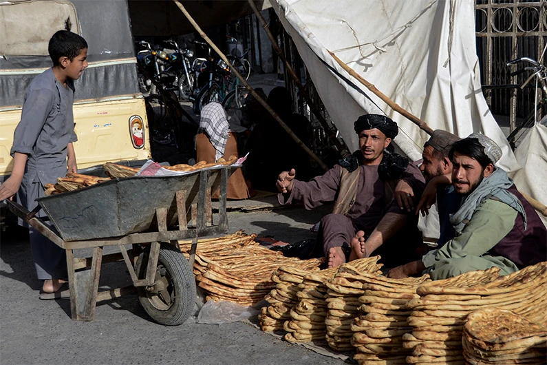 Afghan roadside vendors selling bread wait for customers on the first day of holy fasting month of Ramadan in Kandahar on April 2, 2022. (AFP)
