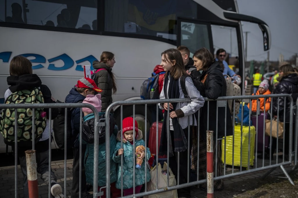 Ukrainian refugees wait to board a bus after crossing the Ukrainian border with Poland at the Medyka border crossing, southeastern Poland. (File/AFP)