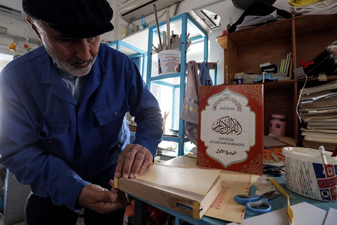 A man glues together a volume during a workshop on the restoration of copies of the Holy Qur'an, Islam’s holy book, in Libya’s capital Tripoli on March 22, 2022. (AFP)