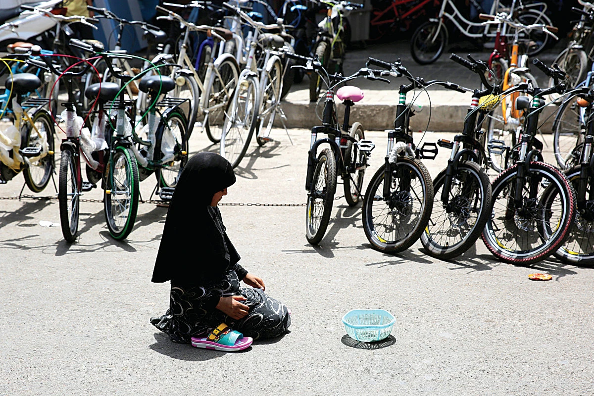 An Iraqi girl begs in the street in front of a bicycle market in the Al-Sadreyh neighborhood, central Baghdad, May 24, 2019. (Photo by Ahmad AL-RUBAYE / AFP)