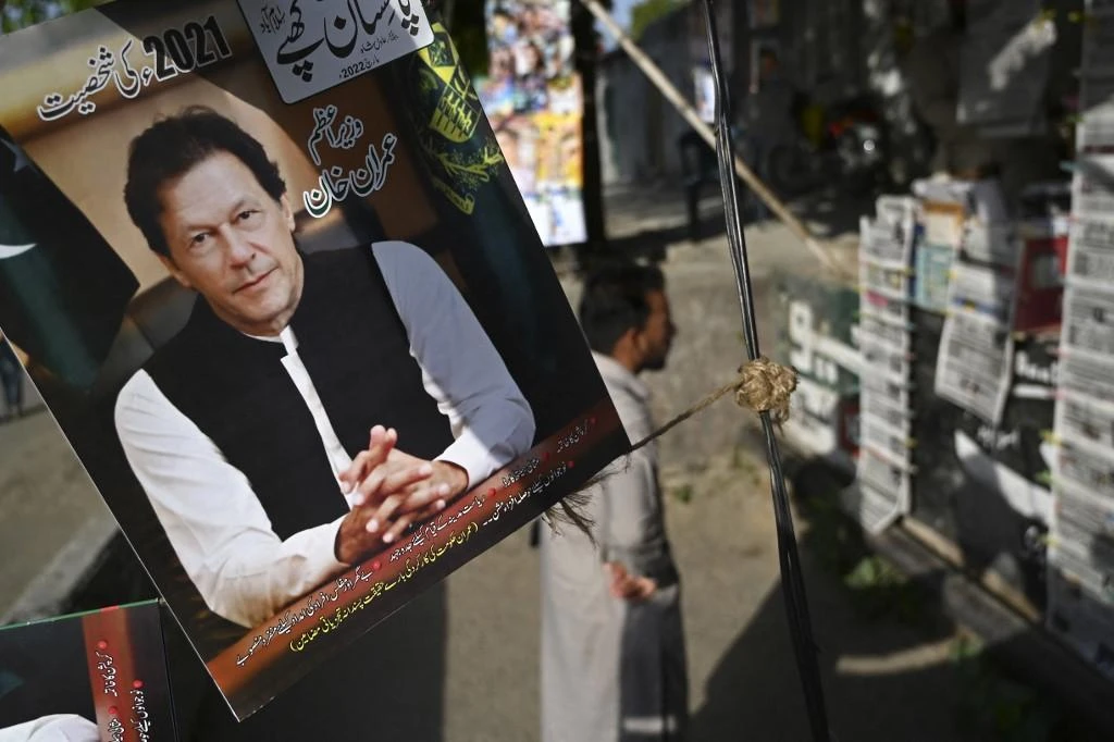 A resident stands beside a picture of Pakistan’s Imran Khan as he looks at the morning newspapers displayed for sale at a roadside stall in Islamabad. (File/AFP)