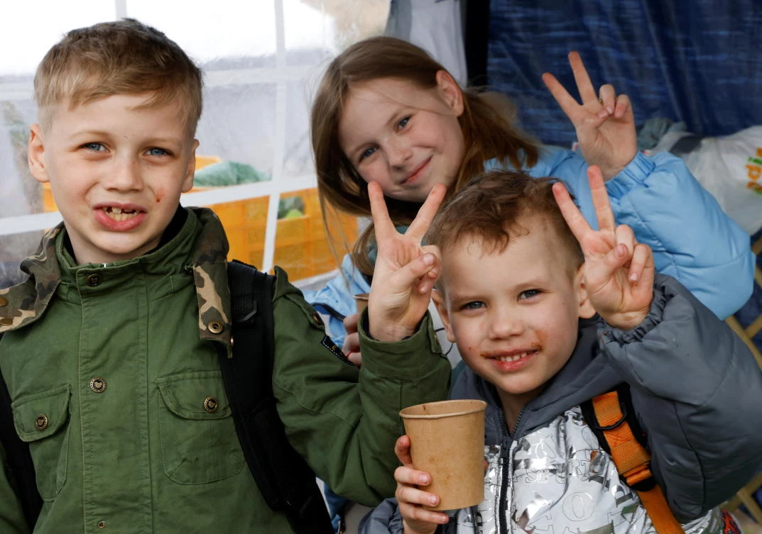 Ukrainian refugees Maxim, Sergej and Nastja pose for a photograph after a 30-hour trip with their parents from the Donetsk region, after crossing the Ukraine-Poland border on Thursday. (Reuters)