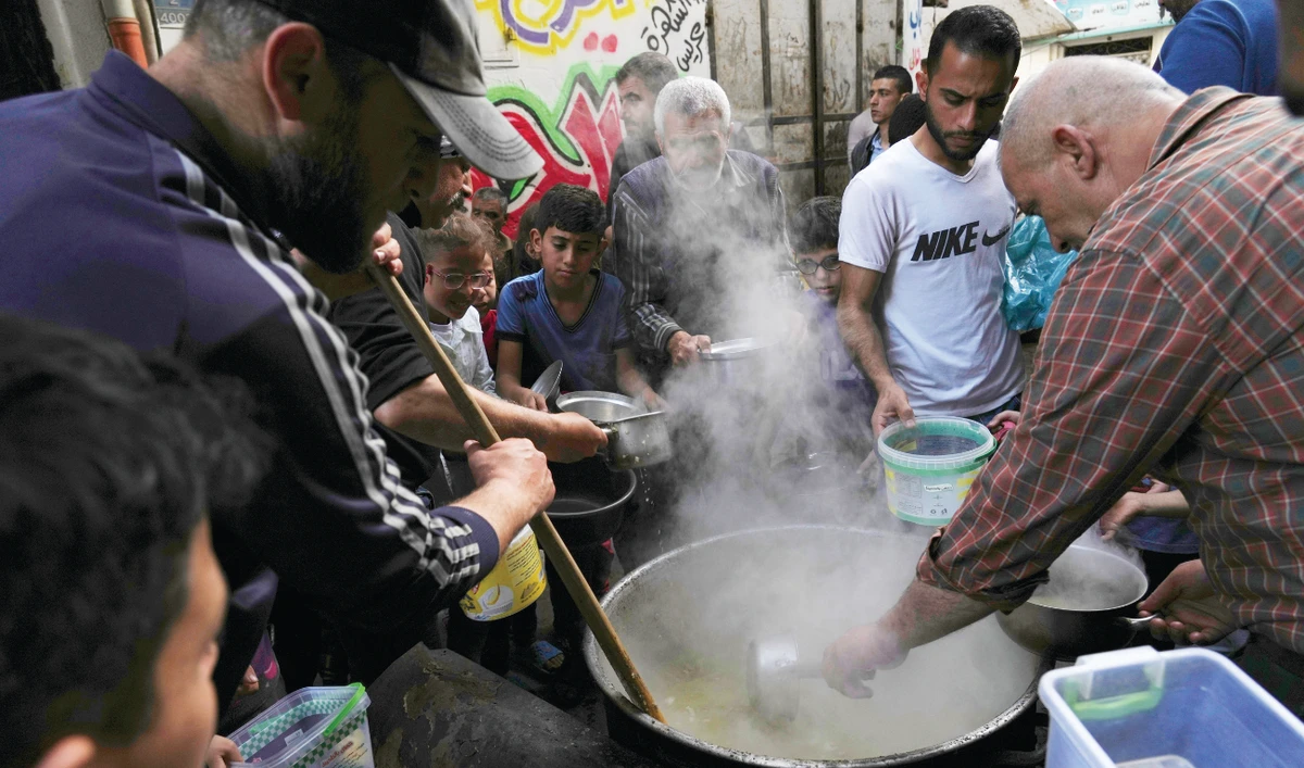 People receive hot wheat soup and porridge before they break their fast at the Shijaiyah neighborhood in Gaza City. (AP)
