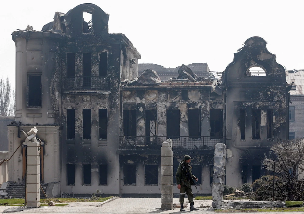 A service members of pro-Russian troops stands near a building burnt during Ukraine-Russia conflict in the southern port city of Mariupol. (Reuters)