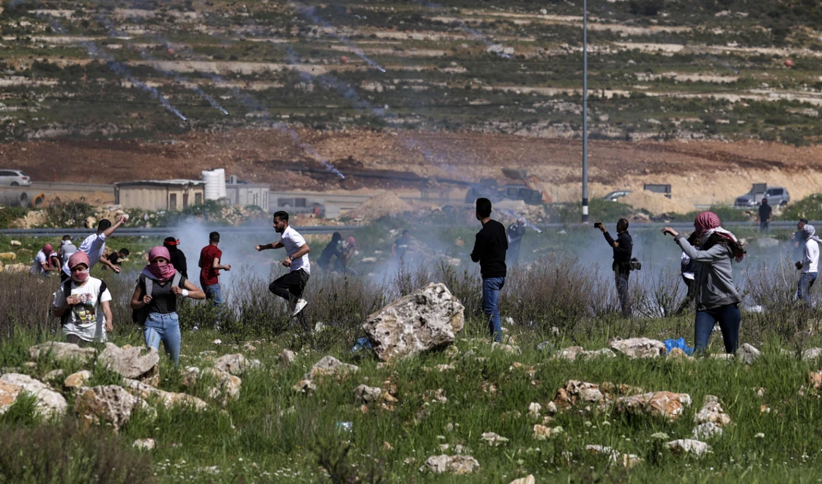 Palestinians run for cover from teargas during clashes with Israeli security forces at the northern entrance of Ramallah, near the Israeli settlement of Beit El, in the occupied West Bank. (AFP/File)