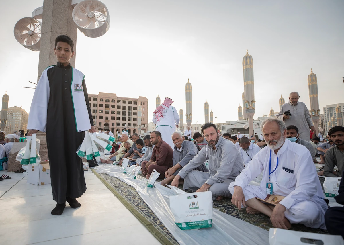 A young volunteer gives out iftar meals to worshippers at the Prophet’s Mosque in Madinah. (@wmngovsa)
