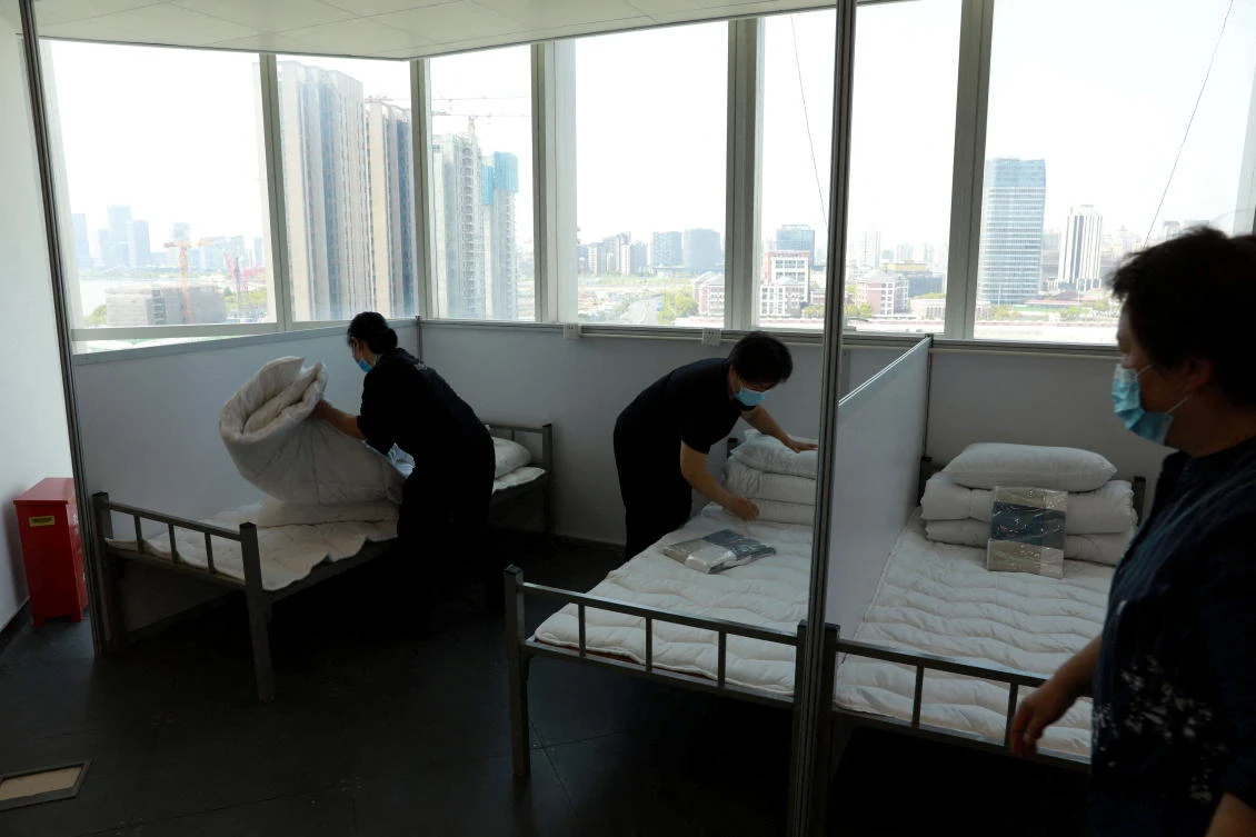 Workers make beds at a 17-storey office building to convert it into a makeshift hospital for the coronavirus disease in Shanghai, China on April 12, 2022. (China Daily via Reuters)