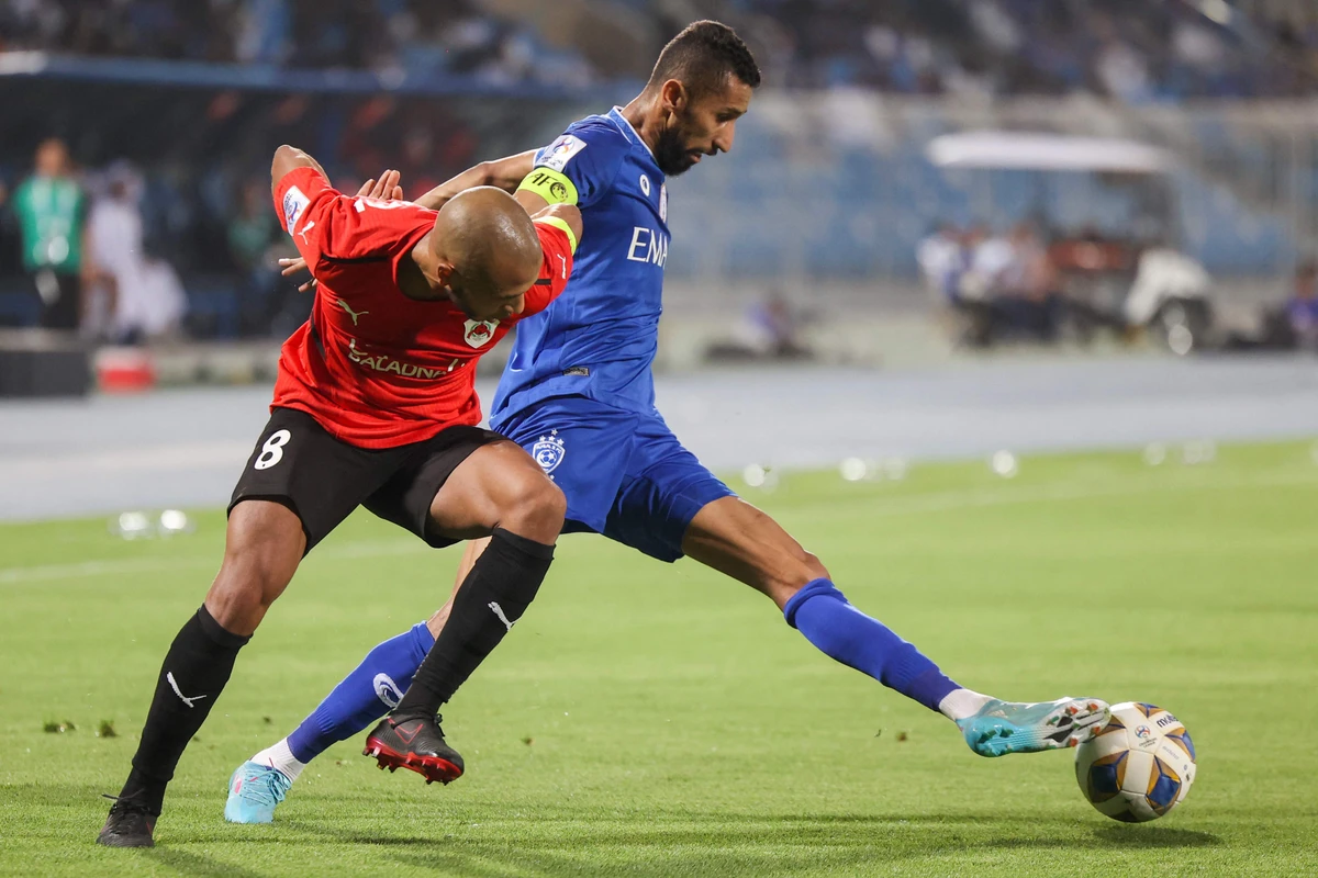 Rayyan's midfielder Yacine Brahimi, left, vies for the ball with Hilal's midfielder Salman Al-Faraj on April 11, 2022. (AFP)
