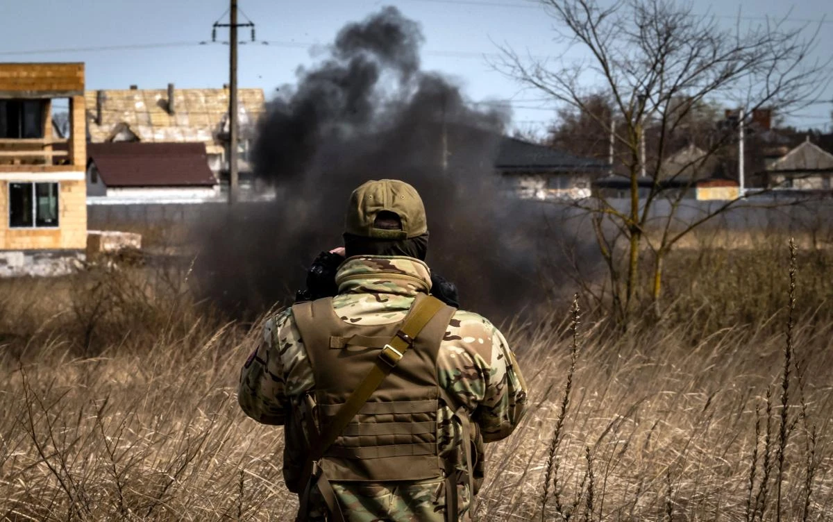 A member of a bomb disposal bomb squad looks at smoke as he works in mine field near Brovary, northeast of Kyiv, on April 14, 2022, amid Russia's military invasion launched on Ukraine. (AFP)