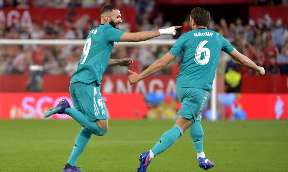 Real Madrid's French forward Karim Benzema (L) celebrates with teammate Real Madrid's Spanish defender Nacho Fernandez after scoring a goal during the Spanish League football match against Sevilla FC on April 17, 2022. (AFP)