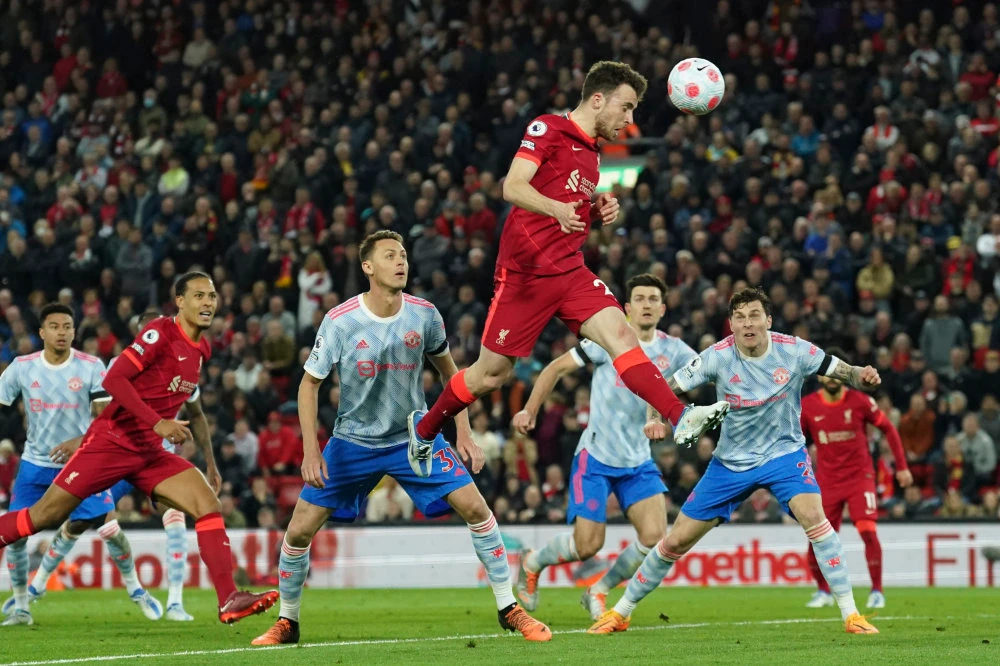 Liverpool's Diogo Jota, top, attempts a head at goal during the English Premier League soccer match between Liverpool and Manchester United at Anfield stadium in Liverpool, England, Tuesday, April 19, 2022. (AP)