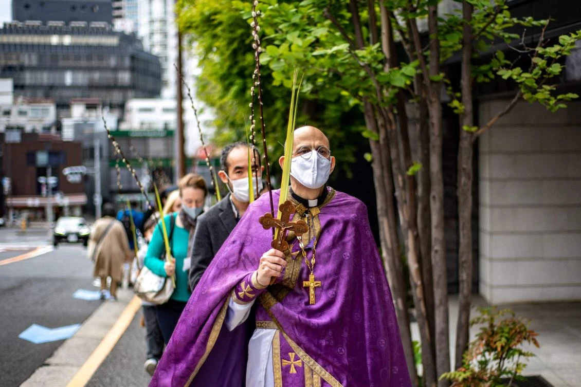 Father Paul Koroluk from the Ukrainian Orthodox Church leads a group of people to walk with willow and palm branches outside a church in Tokyo before attending a service to mark Palm Sunday and pray for peace in Ukraine. (AFP)