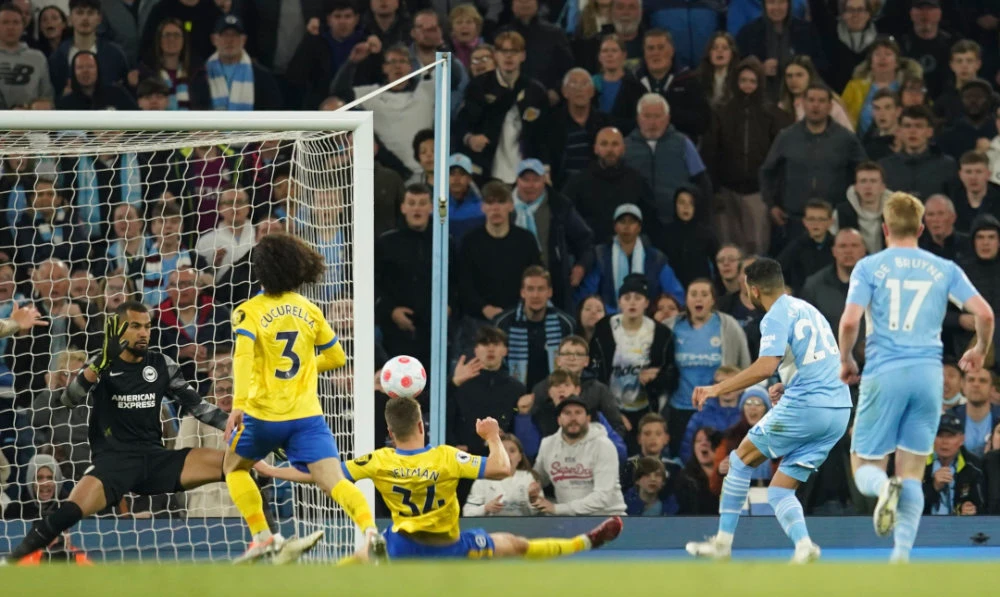 Manchester City's Riyad Mahrez, second right, scores his side's opening goal during their English Premier League football match against Brighton and Hove Albion at the Etihad Stadium in Manchester, England, on April 20, 2022. (AP)