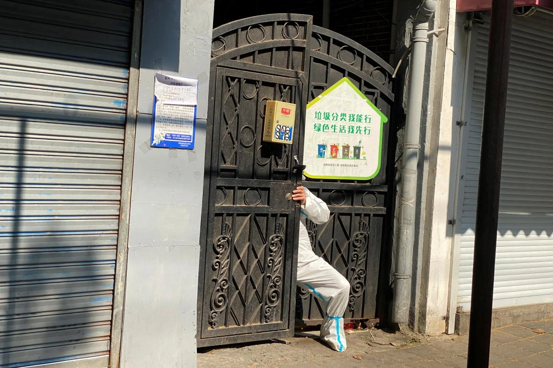 Above, a person in a protective suit squeezes through a locked gate of a residential compound, following the coronavirus disease outbreak in Shanghai on April 21, 2022. (Reuters)