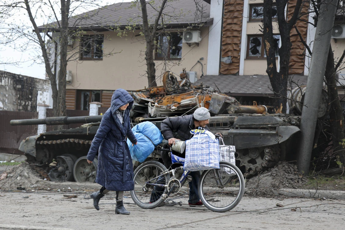 Local civilians walk past a tank destroyed during heavy fighting in an area controlled by Russian-backed separatist forces in Mariupol, Ukraine. (AP)