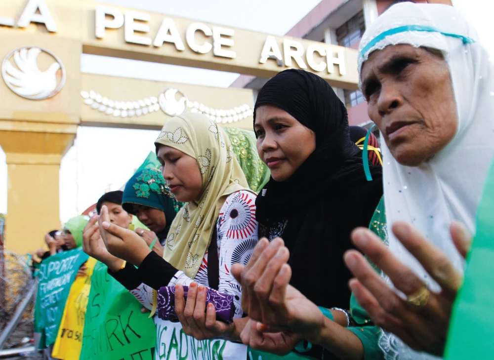Muslim women pray in Manila on Monday after a nationwide peace caravan from Mindanao to show support for the signing of a framework agreement. (Reuters)