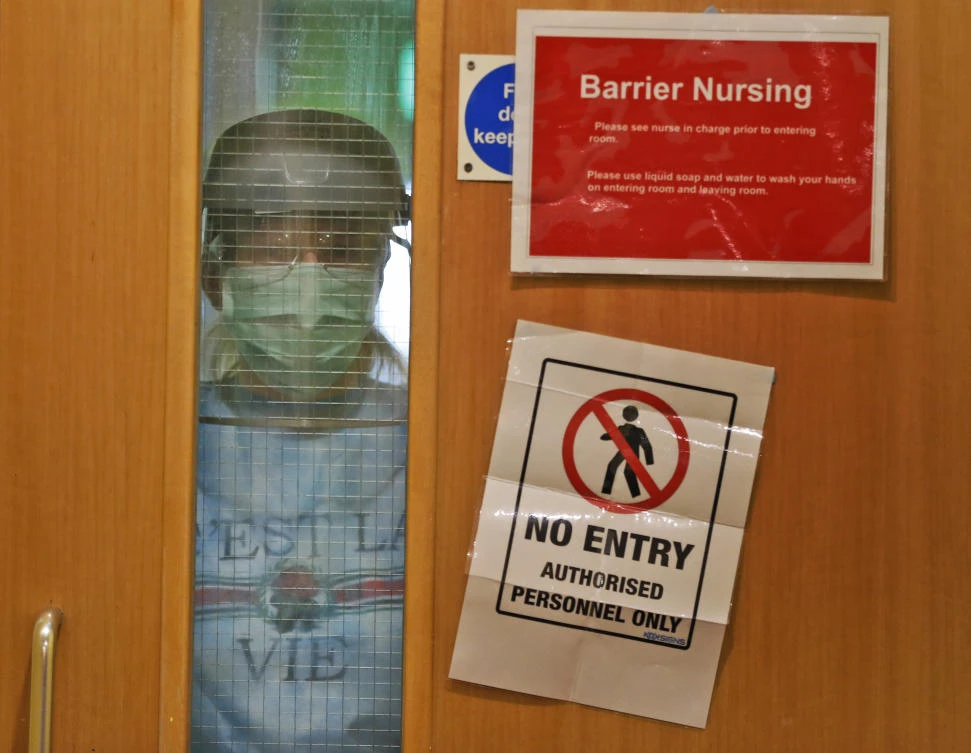 A nurse wearing PPE looks through a window of a closed doorat the Wren Hall care home in Nottingham. (AP)