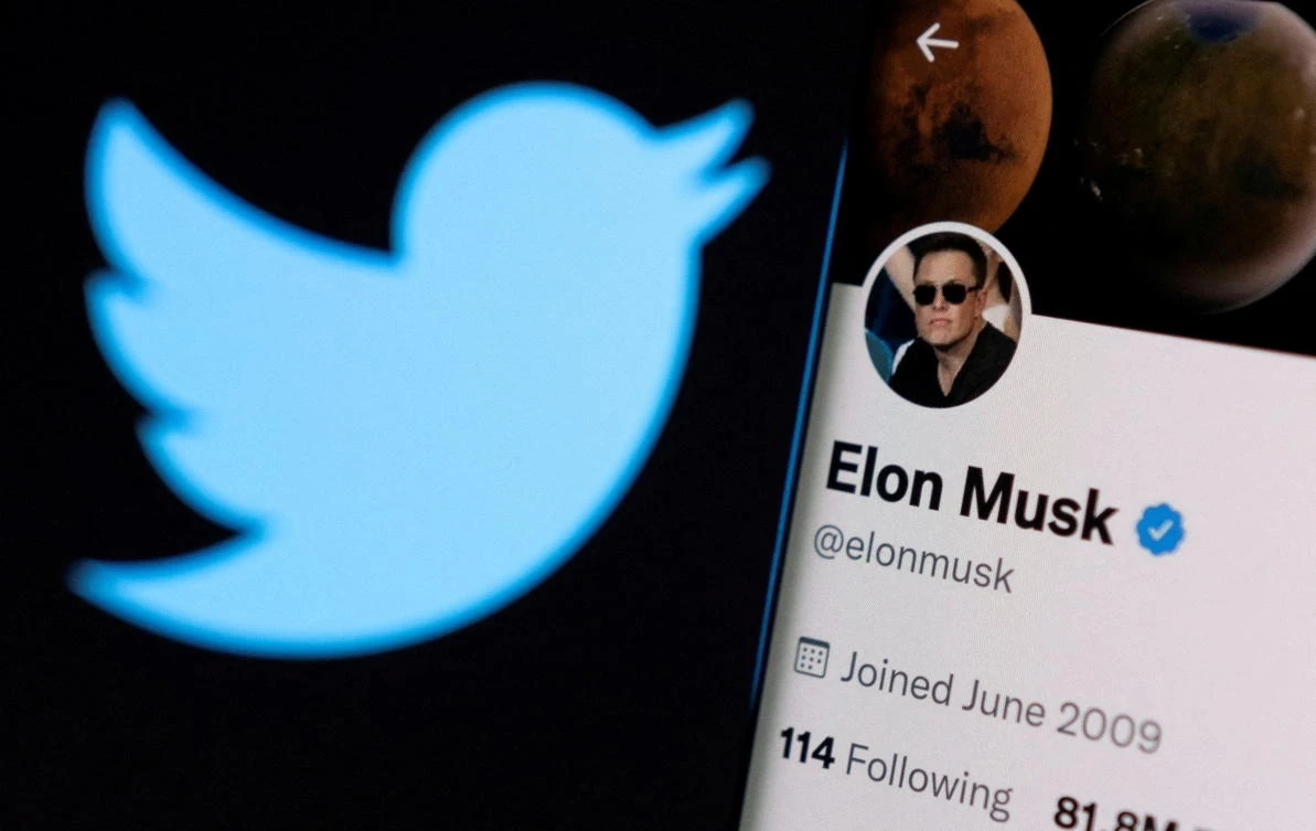Elon Musk’s twitter account is seen on a smartphone in front of the Twitter logo. (Reuters)