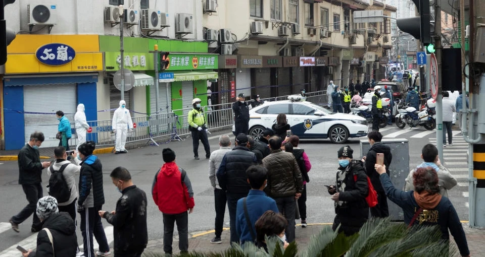 Bystanders watch as police officers and workers in protective suits close off a neighborhood as it is placed under lockdown in Shanghai, China, Jan. 21, 2021. (AP Photo)