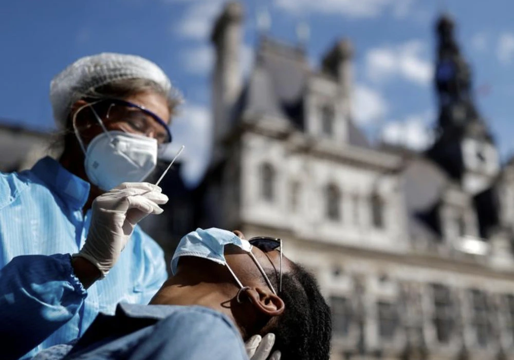 A health worker, wearing a protective suit and a face mask, prepares to administer a nasal swab to a patient at a testing site for the coronavirus disease (COVID-19) installed in front of the city hall in Paris, France. (Reuters/File)