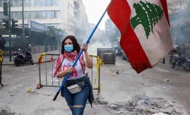 A demonstrator carries the national flag during a protest against the fall in the Lebanese pound and mounting economic hardships, Beirut, Lebanon, Mar. 16, 2021. (Reuters)