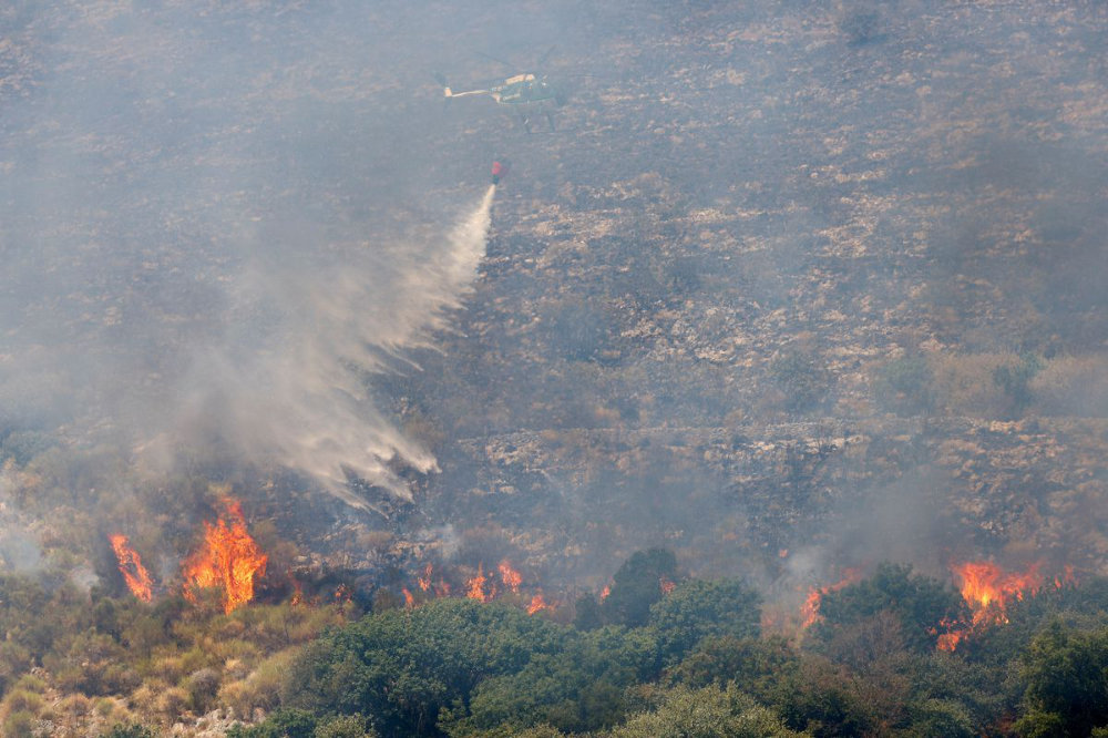 A helicopter drops water to contain a wildfire in the Monte Catillo nature reserve in Tivoli, near Rome, Italy. (Reuters)